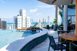 a swimming pool with tables and chairs on a building at Flat Luxo em Boa Viagem - 5min do Aeroporto - perto da praia - Wi-Fi 500mb - check-in 24h in Recife