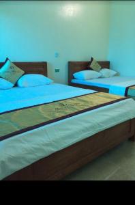 two beds in a bedroom with blue sheets and pillows at Anh Đàm Motel in Vĩnh Phúc