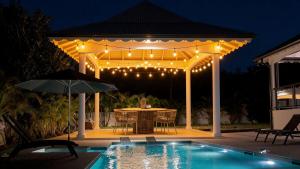a pergola with a table and chairs next to a pool at Villa Kynoa 4 étoiles in Saint-François