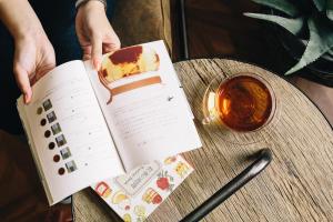 a person reading a book with a piece of cake on a table at Sakura Terrace The Atelier in Kyoto