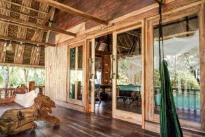 an open living room with wooden walls and windows at Villa Monyet Java in Batukaras