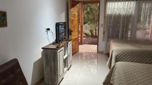 a room with a tv on a stand with a bed at Rukas Huinkaray in Pucón