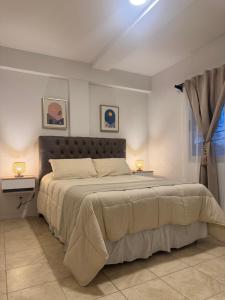 a bedroom with a large bed and two lamps at Campana Suites Becerra in Campana