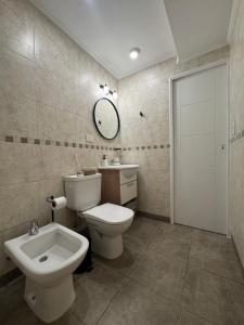 a bathroom with a toilet and a sink and a mirror at Campana Suites Becerra in Campana +22 photos
