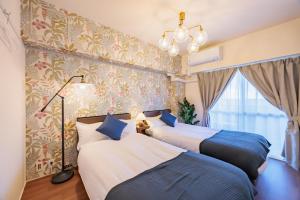 two beds in a room with wallpaper at Minato Marine Stay in Nagoya