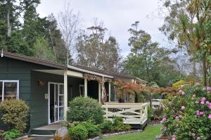 a green house with a white fence and flowers at Creel Lodge in Turangi