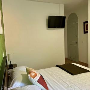a bedroom with a bed with a television on the wall at Casa Bamboo in Mexico City