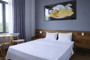 a hotel room with a white bed and a table at Hoa Dã Qùy Hotel 2 in Pleiku