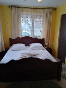 a large bed in a bedroom with a window at NICO-ȘTEF in Vatra Dornei
