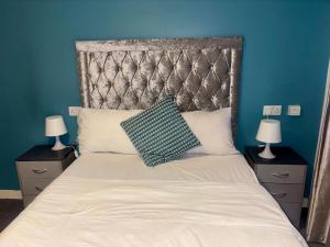 a bedroom with a large bed with a blue wall at Peaceful Urban Retreat in Wolverhampton city in Wolverhampton