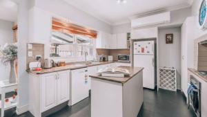 a kitchen with white cabinets and a white refrigerator at Family Cottage in Bendigo