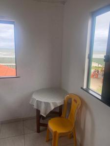 a table and a yellow chair in a room with a window at Cabana Maktub in Uruçuca