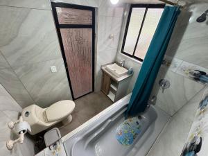 a bathroom with a toilet and a sink and a tub at Hospedaje Las Bromelias - Departamento Familiar in Papallacta