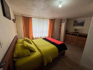 a bedroom with a yellow bed with a window at Hospedaje Las Bromelias - Departamento Familiar in Papallacta
