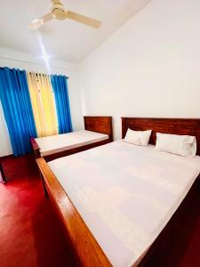 a bedroom with two beds and a blue curtain at Willow Nest Inn in Mahiyangana