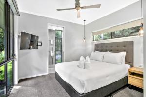 a bedroom with a white bed and a tv at Under the Pecans - 2BR Retreat with Peaceful Scenic Views in Woombye