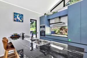 a kitchen with a glass counter and a blue wall at Under the Pecans - 2BR Retreat with Peaceful Scenic Views in Woombye