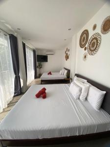 a bedroom with two beds with white sheets and red objects at Villa Talisay Kaputian - Ocean View in Samal