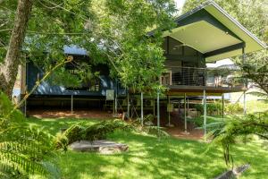 a house with a green roof in the middle of a yard at Under the Pecans - 2BR Retreat with Peaceful Scenic Views in Woombye