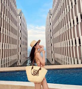 a woman wearing a straw hat and carrying a purse at Apec Mandala Imperial Ocean Tower Mui Ne in Mui Ne