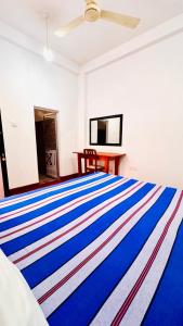 a bedroom with a bed with a colorful striped blanket at Willow Nest Inn in Mahiyangana