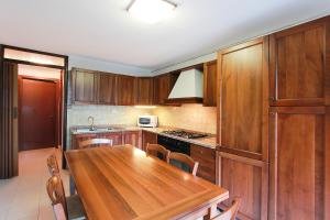 una cucina con armadi in legno e tavolo in legno di Villa Russo a Lignano Sabbiadoro
