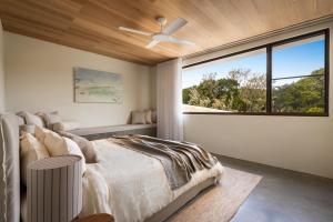 a bedroom with a ceiling fan and a large window at Villa Alcorn in Suffolk Park +19 photos