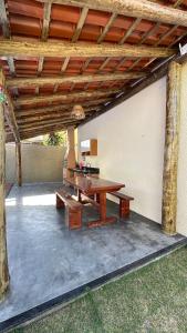 a wooden picnic table under a wooden pergola at Duplex 2 Suites Pool Barbecue Air in Santa Cruz Cabrália +31 photos