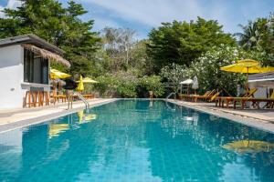 a swimming pool with tables and umbrellas in a resort at Sea Escapes Villas in Thong Sala