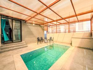 a large swimming pool in a building with a table and chairs at SeaLara Resorts in Covelong