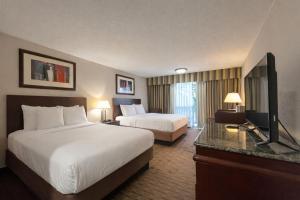 a hotel room with two beds and a flat screen tv at Derby Hotel & Suites in Clarksville