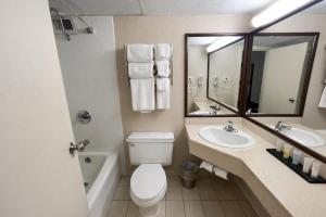 a bathroom with a toilet and a sink and a mirror at Derby Hotel & Suites in Clarksville