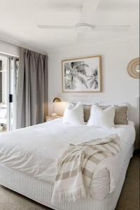 a white bedroom with a large white bed with white pillows at Noosa Parade Holiday Inn in Noosa Heads +100 photos