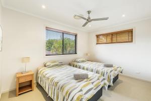 two beds in a room with two windows at Amarco Spacious Riverfront with Sunset Views in Iluka