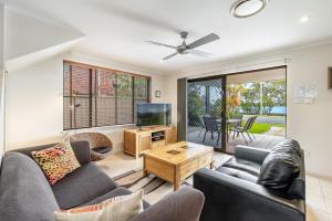 a living room with two couches and a flat screen tv at Amarco Spacious Riverfront with Sunset Views in Iluka