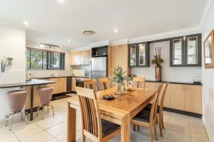 a kitchen and dining room with a wooden table and chairs at Amarco Spacious Riverfront with Sunset Views in Iluka