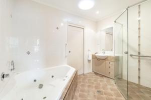 a white bathroom with a tub and a sink at Amarco Spacious Riverfront with Sunset Views in Iluka +12 photos
