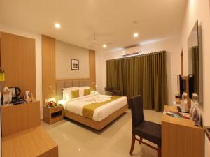 a hotel room with a bed and a desk and a chair at Hotel Salkara Chavakkad in Manattala
