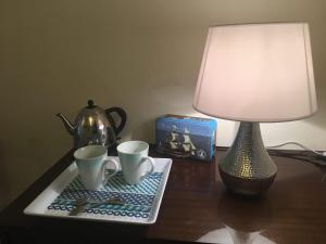 a table with a lamp and two cups on a table at Logis des Lauriers Roses in Marennes