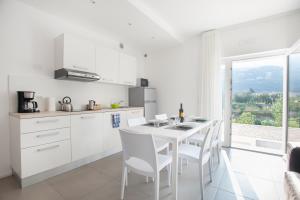 ナーゴ・トルボレにあるAppartamenti Villa al Fiumeの白いキッチン(テーブル、椅子付)、窓