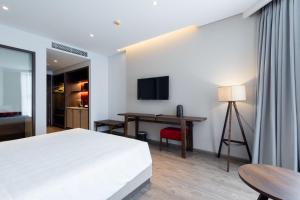 a bedroom with a bed and a desk and a television at Mandala Casa del Sol Mũi Né in Mui Ne