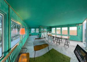 a green room with a table and chairs and windows at Padi Box Homestay in Sekinchan