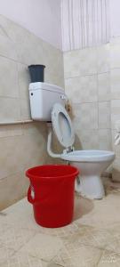 a bathroom with a toilet and a red bucket at Kurnool Homestay in Kurnool