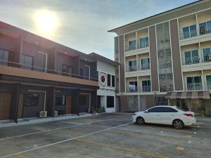 a white car parked in a parking lot in front of a building at La Maison 230 in Ban Khlong Samrong