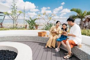 a family sitting on a bench looking at their cell phones at THE SENAGAJIMA STORYLINE in Tomigusuku