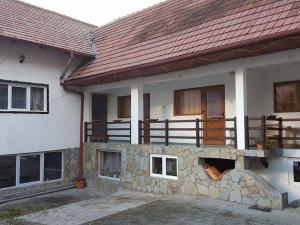 a house with a stone wall and a roof at Pensiunea Cristomar in Bran