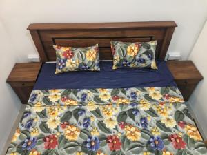 a bed with a floral comforter and two pillows at Minsara Villa in Ahangama