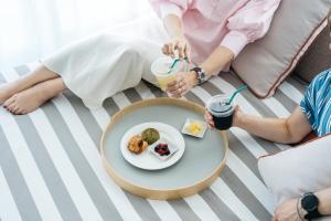 two people sitting on a couch with a table with a plate of food at THE SENAGAJIMA STORYLINE in Tomigusuku