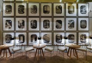 a room with tables and chairs in front of a wall with pictures at H10 Casa Mimosa 4* Sup in Barcelona