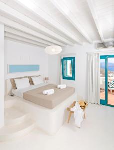 ein weißes Schlafzimmer mit einem Bett und einem Balkon in der Unterkunft Astypalaia Hotel Palace in Astypalea-Stadt